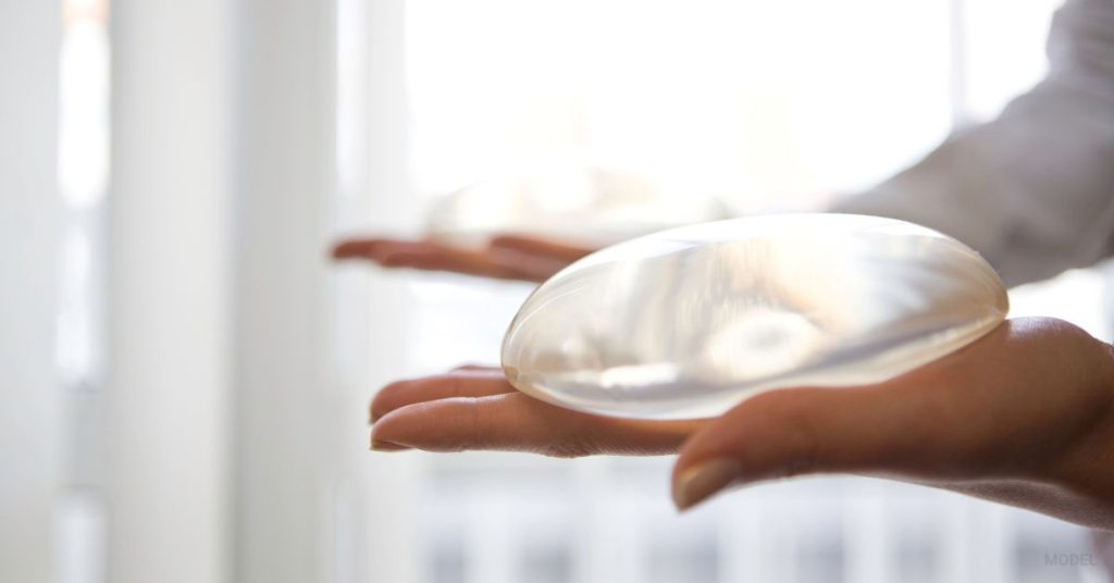 doctor showing off the difference between silicon and saline breast implants (MODEL)